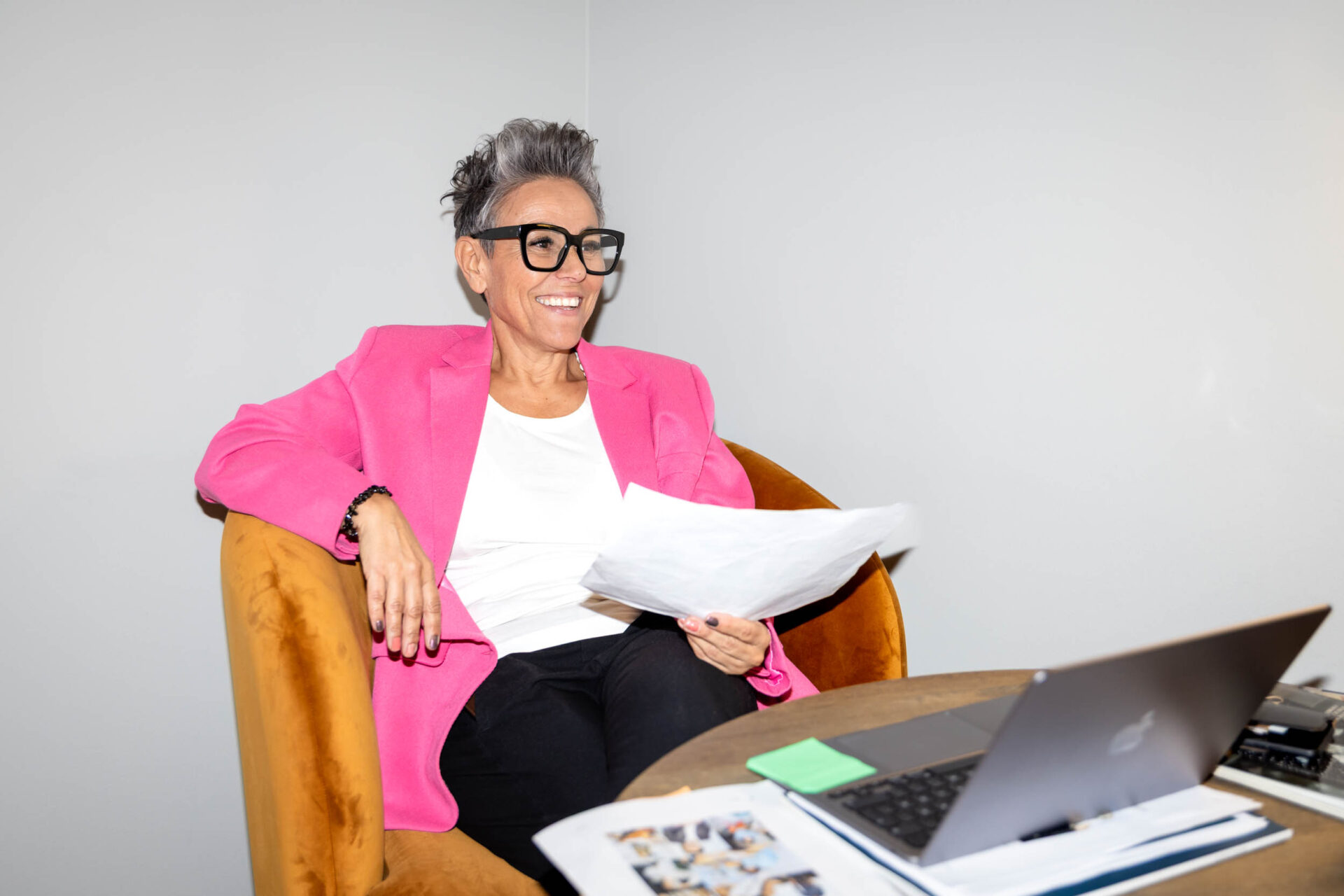 Inköpsassistent i rosa kostym arbetar fokuserat vid dator på ett kontor.