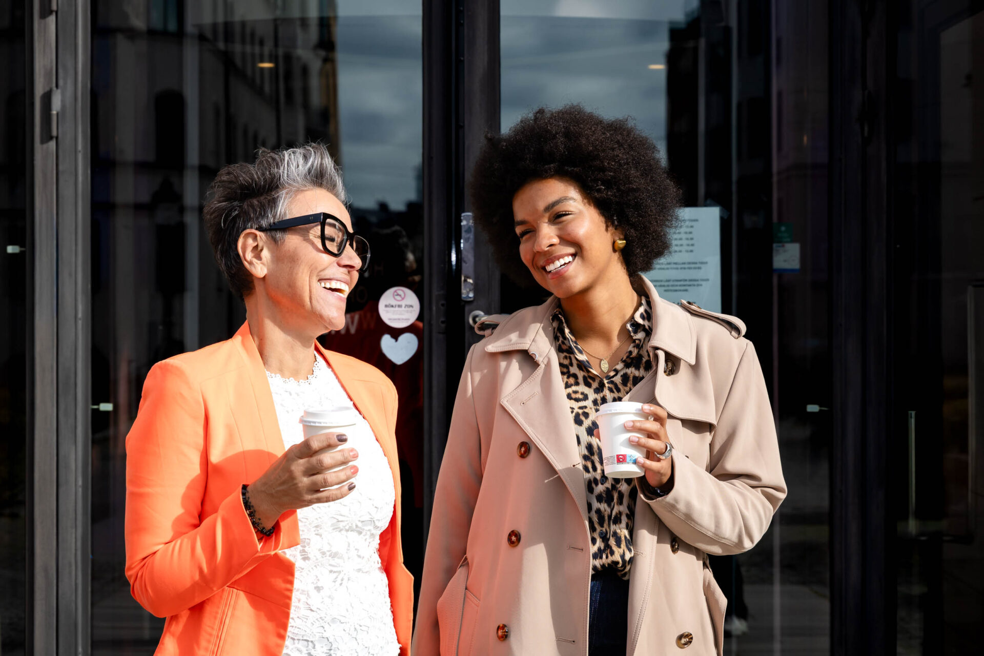 Två receptionister står utanför kontoret, leende och redo att ta emot besökare.